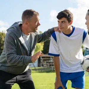 Entrenador motivando a su equipo durante una charla, con los jugadores atentos y enfocados, listos para la próxima acción en el partido.