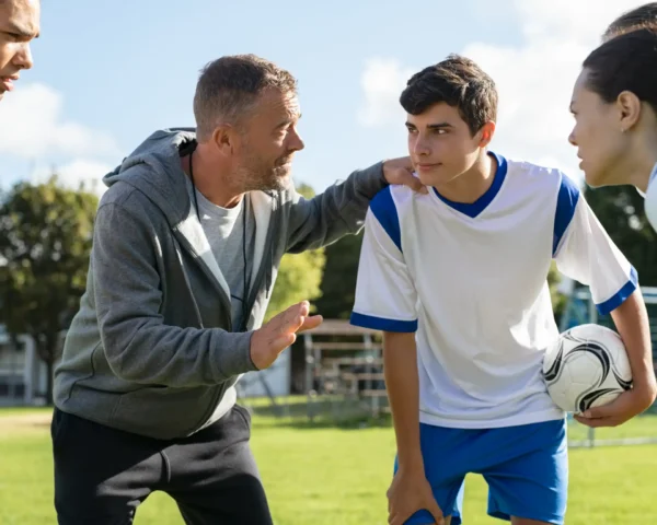 Entrenador motivando a su equipo durante una charla, con los jugadores atentos y enfocados, listos para la próxima acción en el partido.