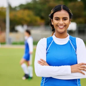 Chica sonriente liderando a su equipo deportivo, con el grupo de fondo mostrando unidad y motivación durante un evento.