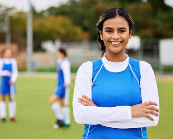 Chica sonriente liderando a su equipo deportivo, con el grupo de fondo mostrando unidad y motivación durante un evento.