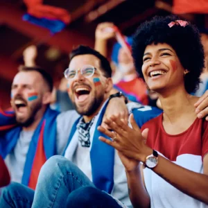Aficionados felices animando en un estadio, reflejando la emoción y pasión que se vive en los eventos deportivos bien gestionados.