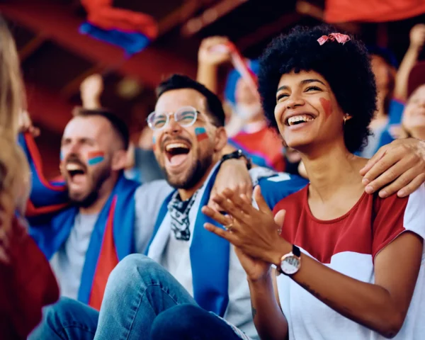 Aficionados felices animando en un estadio, reflejando la emoción y pasión que se vive en los eventos deportivos bien gestionados.