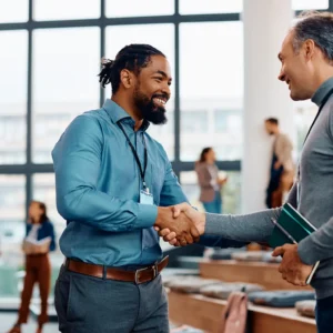 Dos profesionales estrechándose la mano en un evento corporativo, representando la planificación y éxito en la gestión de eventos.